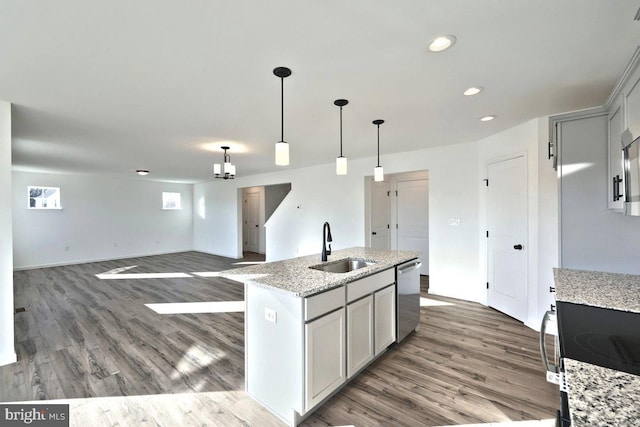 kitchen with stainless steel dishwasher, light stone countertops, wood finished floors, a sink, and decorative light fixtures