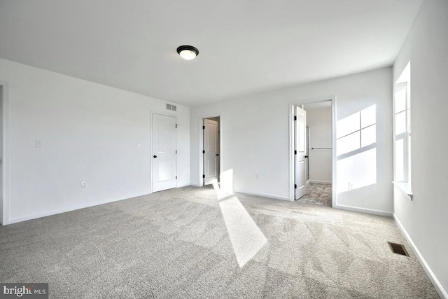 carpeted spare room featuring visible vents and baseboards