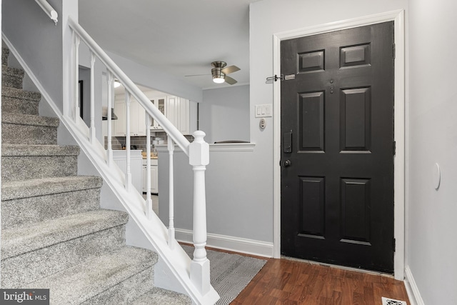 entryway with wood finished floors, ceiling fan, baseboards, and stairs