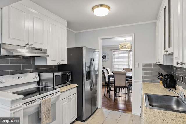kitchen featuring crown molding, white cabinets, under cabinet range hood, a sink, and stainless steel appliances