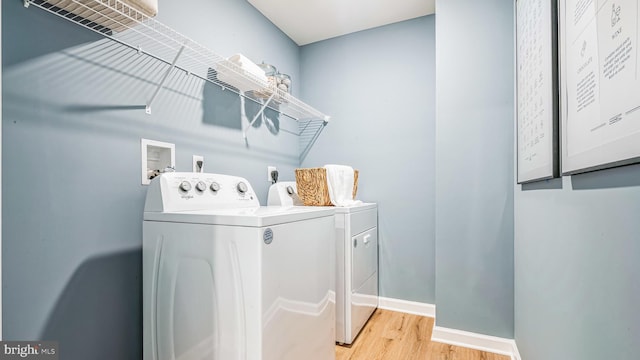laundry room featuring light wood finished floors, baseboards, washer and dryer, and laundry area