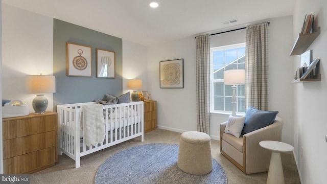 carpeted bedroom featuring baseboards, visible vents, and a crib