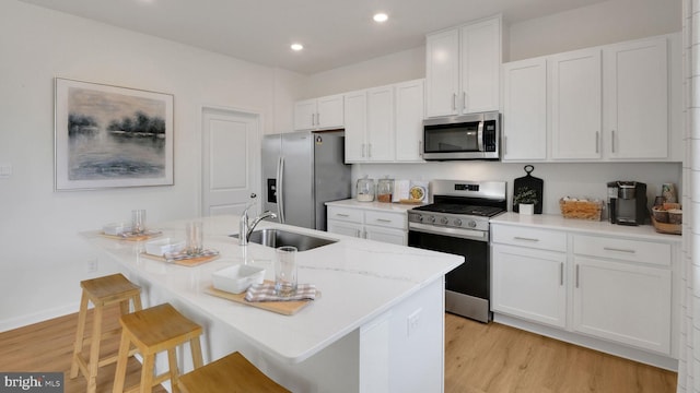 kitchen with white cabinetry, light wood-style floors, a sink, and stainless steel appliances