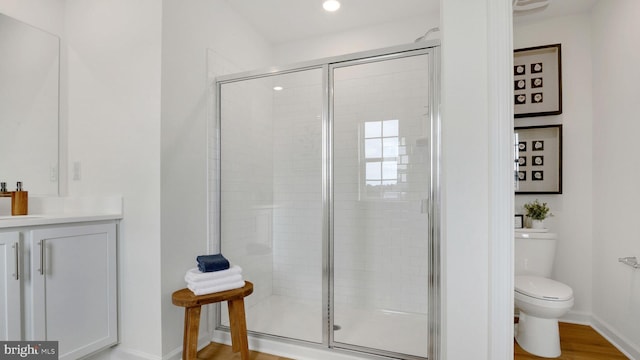 bathroom with baseboards, vanity, toilet, and a shower stall