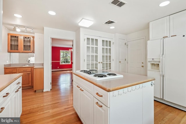 kitchen with white appliances, visible vents, baseboard heating, and light wood finished floors