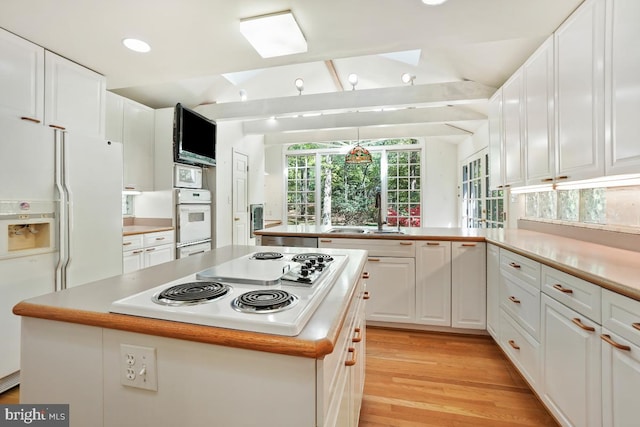 kitchen with a kitchen island, a sink, white cabinets, a peninsula, and white appliances