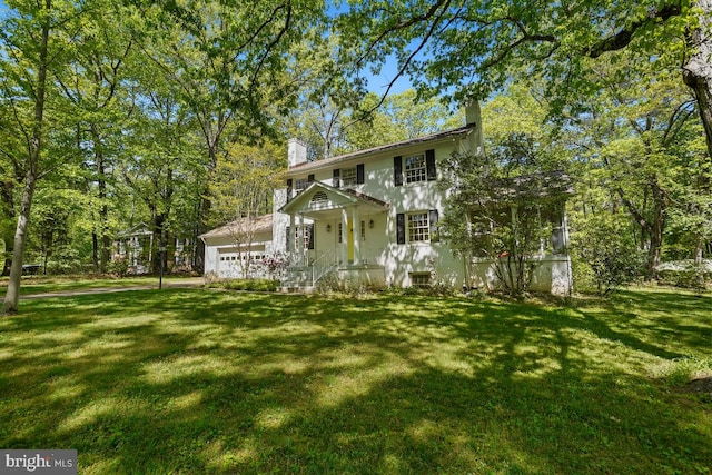 view of front facade with a garage, a chimney, and a front lawn