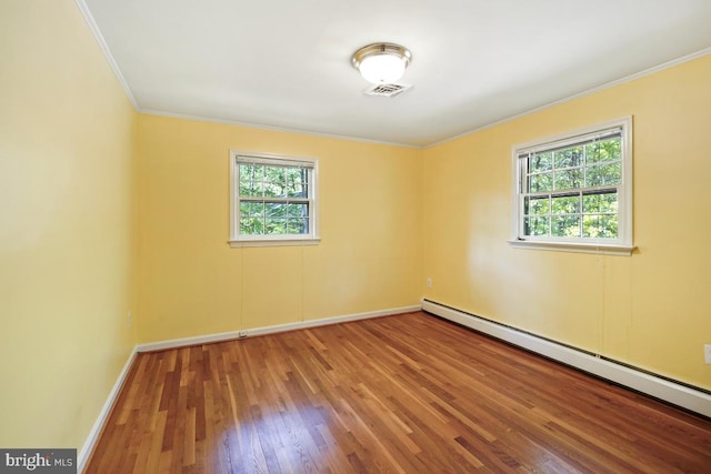 spare room featuring baseboards, wood finished floors, a baseboard radiator, visible vents, and ornamental molding