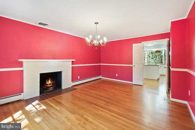 unfurnished living room featuring visible vents, an inviting chandelier, a brick fireplace, wood finished floors, and a baseboard heating unit