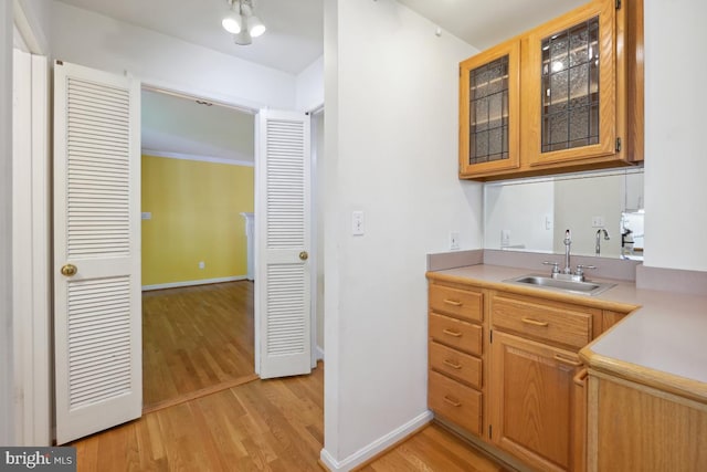 bar with a sink, baseboards, and light wood finished floors