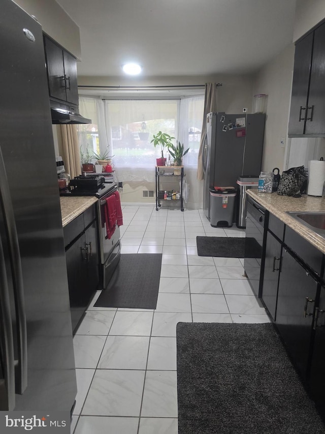 6112 Armor Dr, Clinton, MD 20735 - kitchen with appliances with stainless steel finishes, dark cabinetry, under cabinet range hood, and light marble finish flooring