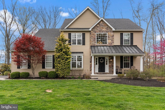 view of front facade with metal roof, a standing seam roof, a front lawn, and covered porch