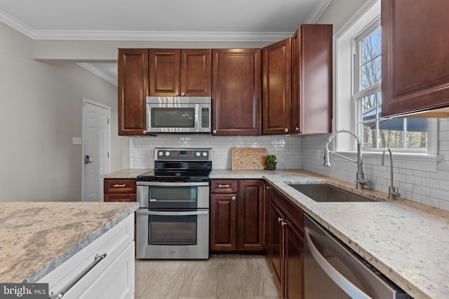 kitchen featuring stainless steel appliances, a sink, backsplash, crown molding, and light stone countertops