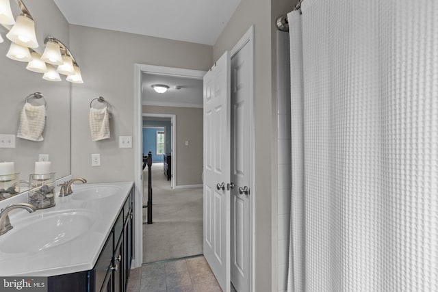 bathroom with crown molding, a notable chandelier, a sink, and double vanity