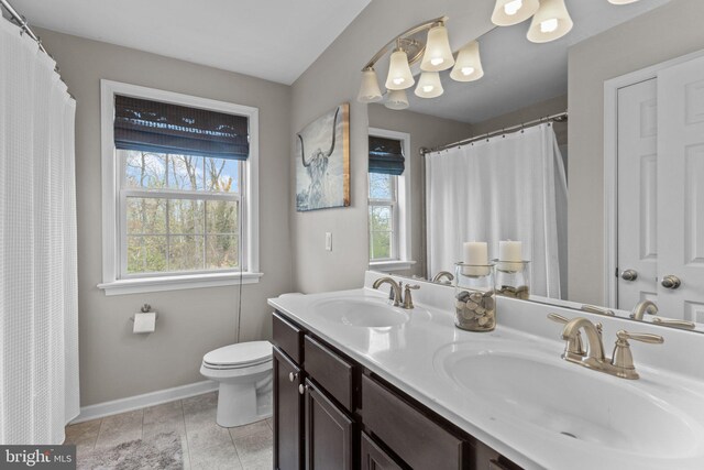 full bathroom with double vanity, toilet, baseboards, and a sink