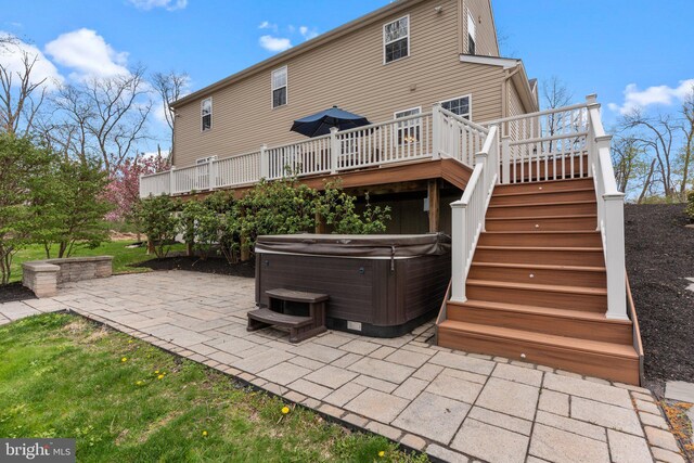 back of property with a hot tub, a deck, a patio, and stairs