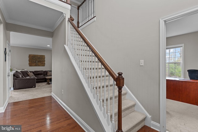 staircase featuring wood finished floors, crown molding, and baseboards