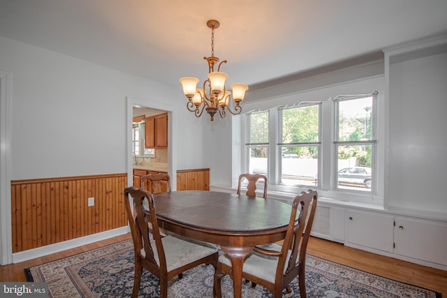 dining space featuring an inviting chandelier, wainscoting, light wood-style flooring, and a healthy amount of sunlight