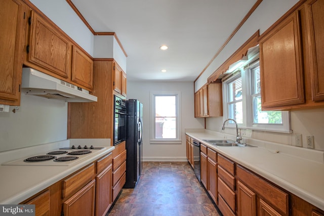 kitchen with light countertops, under cabinet range hood, brown cabinets, a sink, and black appliances