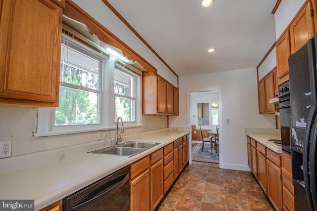 kitchen featuring a sink, dishwasher, light countertops, stone finish floor, and baseboards