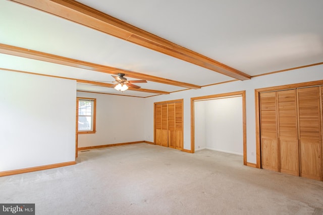 unfurnished bedroom featuring baseboards, beam ceiling, and light carpet