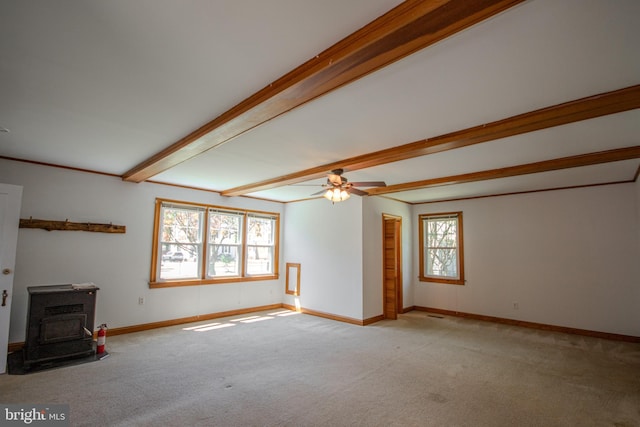 unfurnished living room featuring a wood stove, light carpet, beamed ceiling, baseboards, and ceiling fan