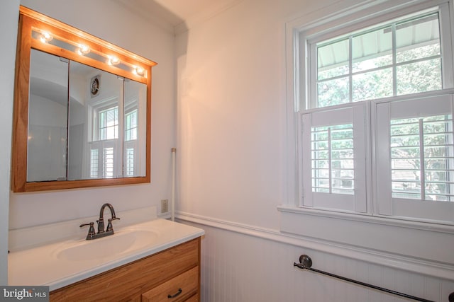 bathroom featuring plenty of natural light, wainscoting, crown molding, and vanity