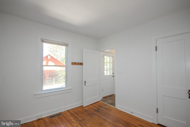 interior space with baseboards, visible vents, a wealth of natural light, and wood finished floors