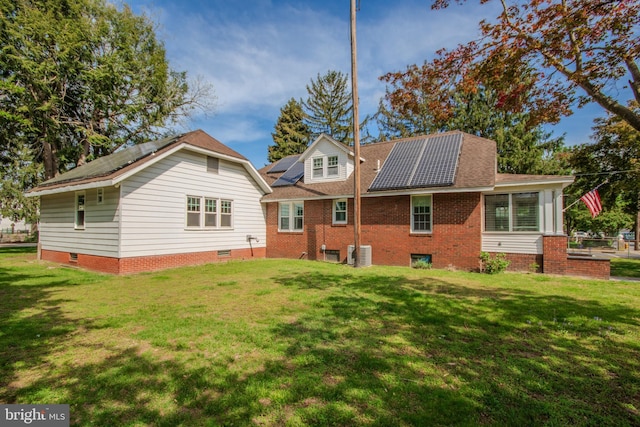 back of property featuring a yard and solar panels