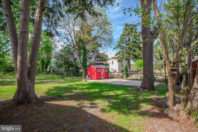 view of yard with fence, a storage unit, an outbuilding, and a patio area