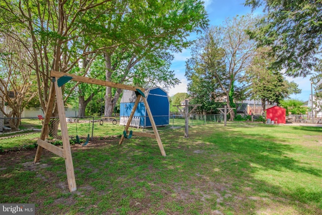 view of jungle gym featuring a yard, fence, a storage shed, and an outdoor structure