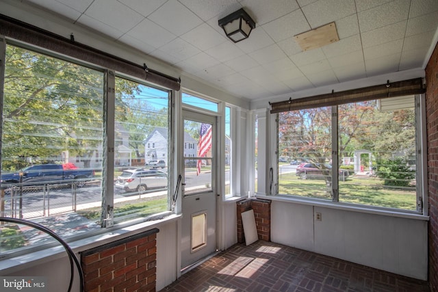 unfurnished sunroom featuring brick patterned floor and a wealth of natural light