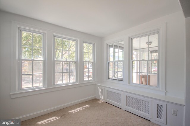 unfurnished sunroom with baseboards and carpet flooring