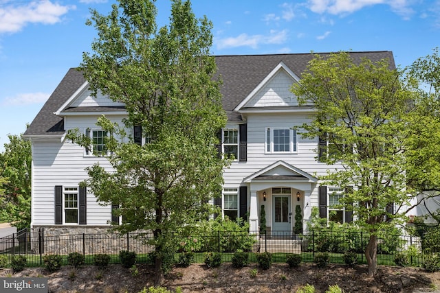 view of front of property with a shingled roof and a fenced front yard