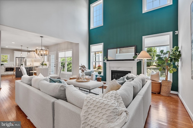 living room featuring a wealth of natural light, a high ceiling, a premium fireplace, and a notable chandelier