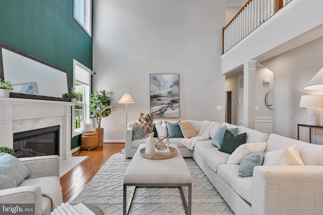 living area with visible vents, a towering ceiling, a premium fireplace, and hardwood / wood-style flooring