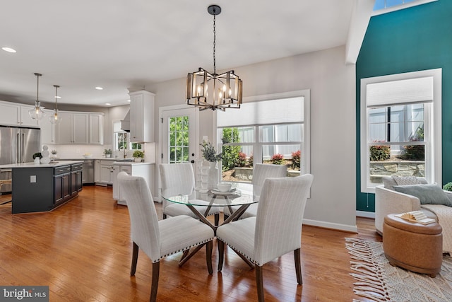 dining space with recessed lighting, baseboards, a chandelier, and light wood-type flooring
