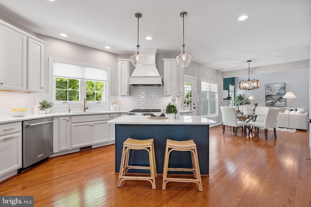 kitchen with white cabinets, a sink, dishwasher, custom range hood, and tasteful backsplash
