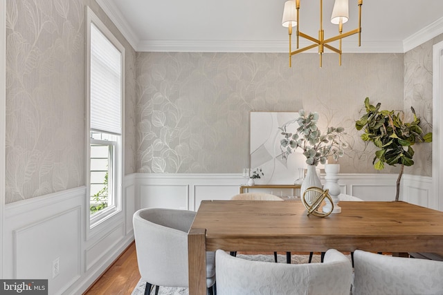 dining room featuring wood finished floors, a notable chandelier, a wealth of natural light, and wallpapered walls