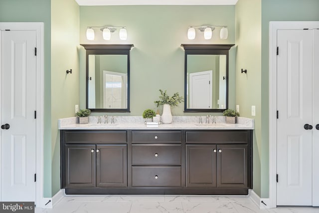 full bathroom featuring baseboards, a sink, marble finish floor, and double vanity