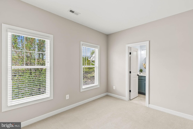 empty room featuring baseboards, visible vents, and light carpet