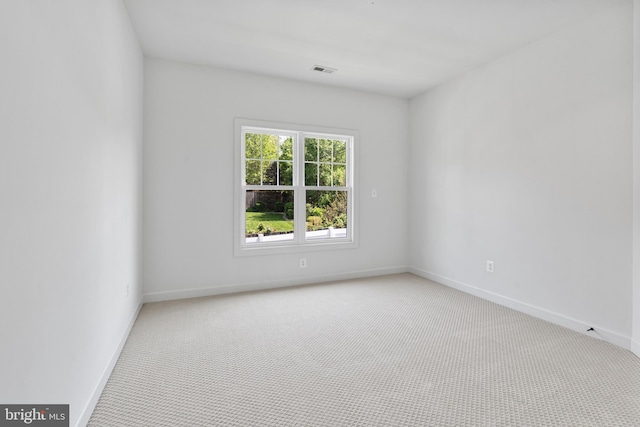 spare room featuring baseboards, visible vents, and carpet