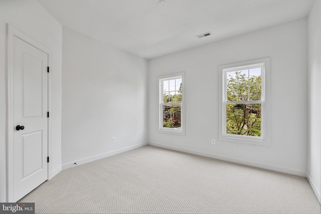 unfurnished room with baseboards, visible vents, and light carpet