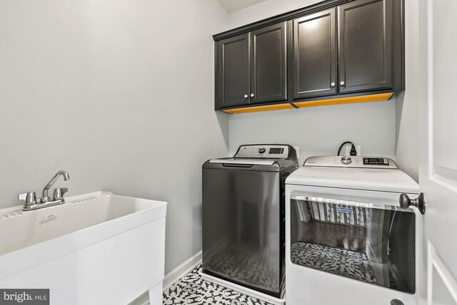 clothes washing area with baseboards, a sink, cabinet space, and washer and clothes dryer