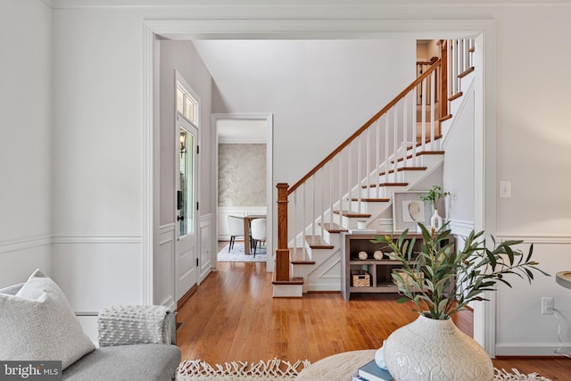 foyer entrance with stairway, a wainscoted wall, and wood finished floors