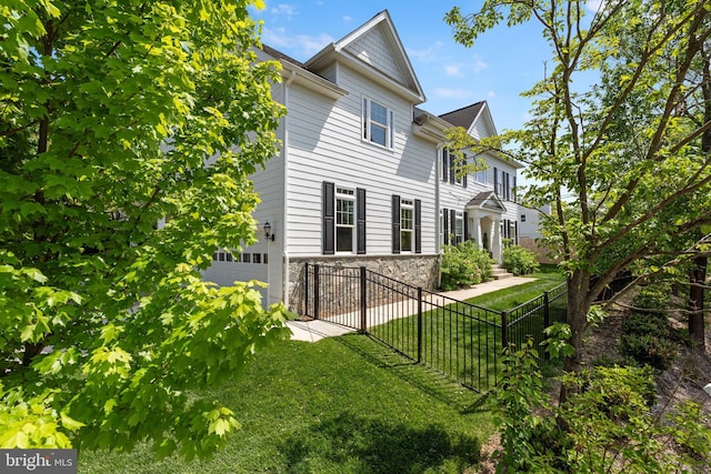 view of side of property with a yard, fence, and stone siding