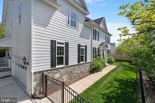 4950 34th St N, Arlington, VA 22207 - view of side of property with fence, a lawn, a garage, and stone siding