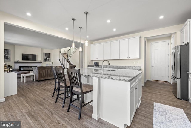 7269 Liberty Ct, Ruther Glen, VA 22546 - kitchen featuring wood finished floors, a sink, freestanding refrigerator, white cabinets, and light stone countertops