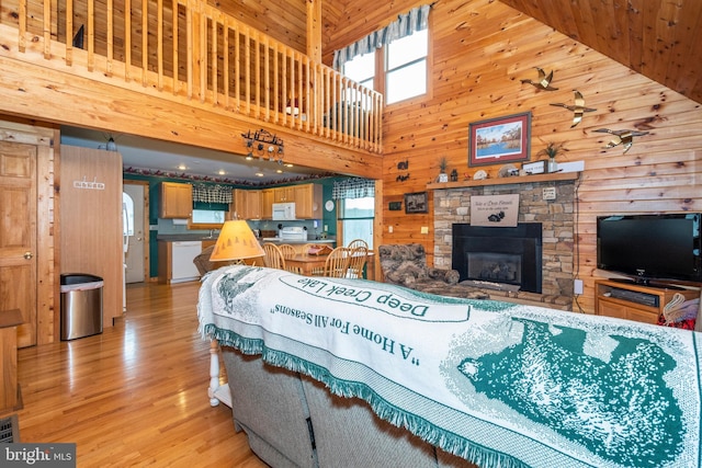 134 Highland Ave, Accident, MD 21520 - living area featuring light wood-style flooring, a towering ceiling, a stone fireplace, and wooden walls