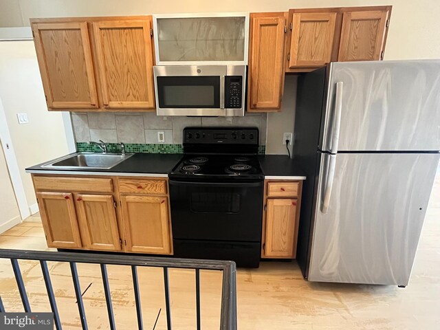 1921 W Diamond St, Philadelphia, PA 19121 - kitchen with tasteful backsplash, light wood-type flooring, a sink, dark countertops, and appliances with stainless steel finishes